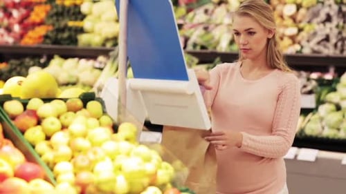 Woman in Supermarket Weighing Fruit Into Bag