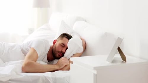 Man Waking up and Stretching in Bed