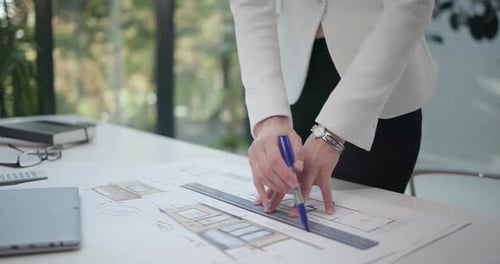 Eine junge Architektin betrachtet bei ihrer Arbeit die Baupläne eines Hauses oder einer Wohnung auf ihrem Schreibtisch