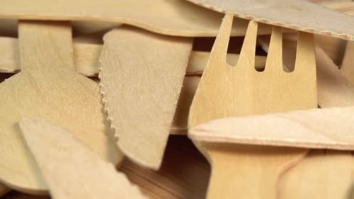 La
vajilla desechable ecológica de madera gira sobre la mesa de madera. Pila de cucharas de madera, tenedores