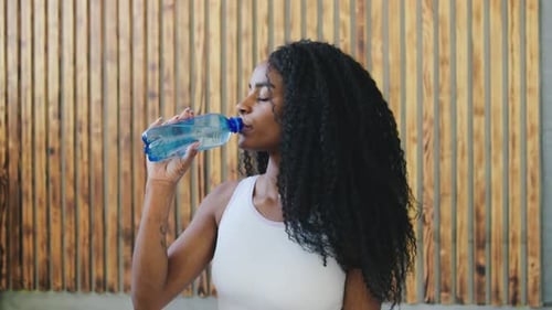 Young Woman Drinks Water, Puts Hands Together