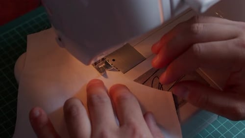 Top front view of sewing pulling fabric through guided by operator's hands