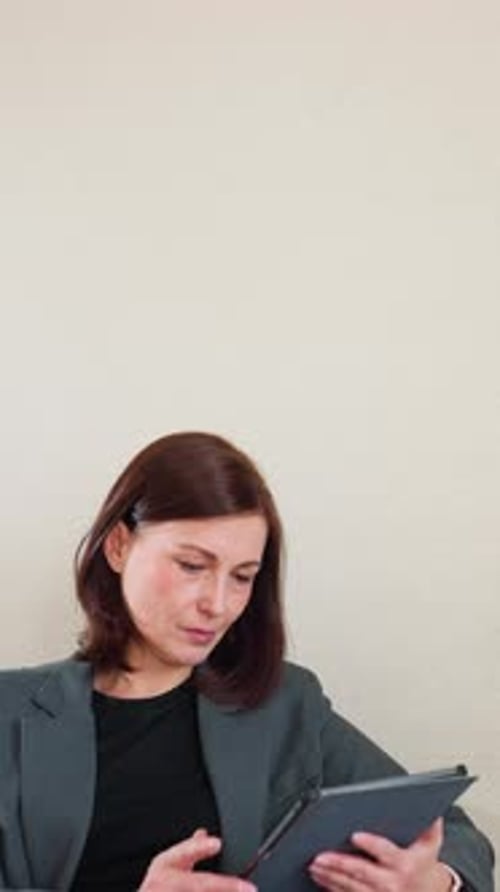 Businesswoman Browsing Tablet in Modern Office with Green Plant Decor