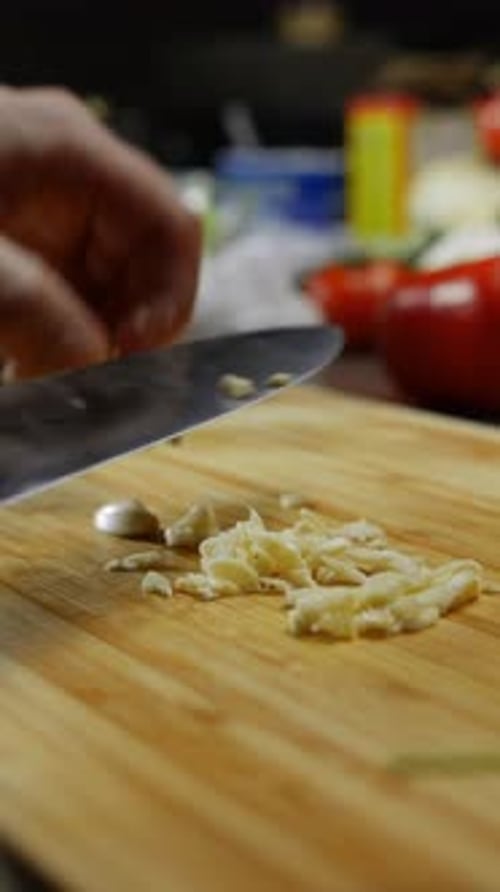 Men's Hands are Chopping a Clove of Garlic