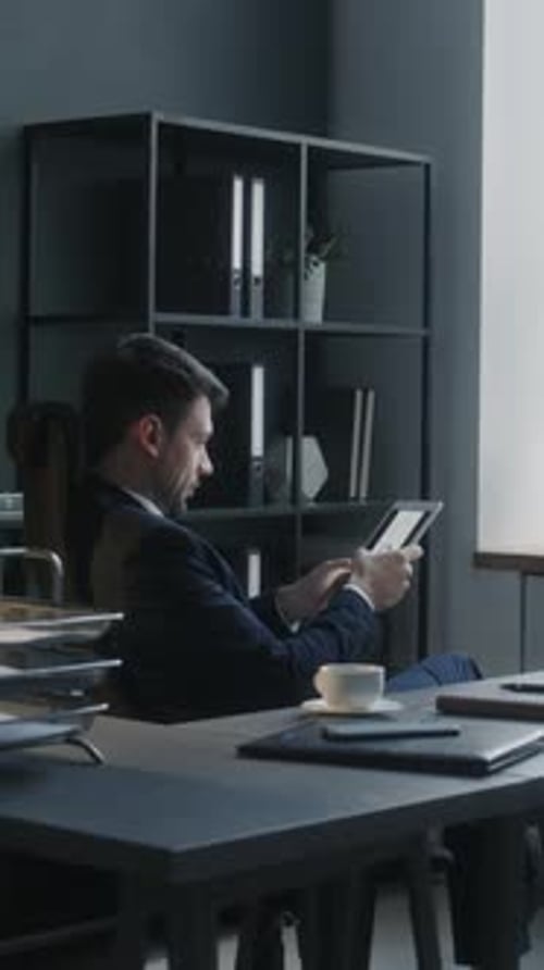 Businessman Reviewing Charts on Tablet at Office Workplace