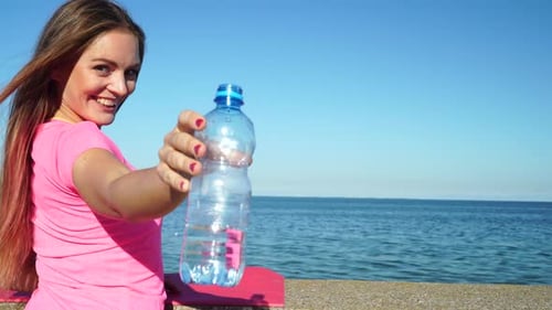 Woman Drinking Water After Exercising by the Ocean