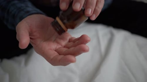 Un anciano se vierte tabletas de antibióticos en la mano