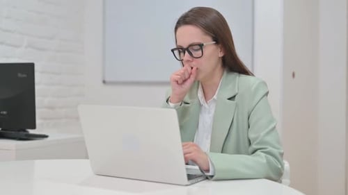 Woman Coughing While Working on Laptop in Office