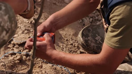 Soldiers Assembling Explosive Device in Arid Environment