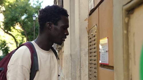 un homme africain qui ne reçoit pas de réponse sur l'interphone part mécontent