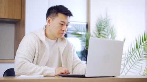 Young Adult Working on Laptop Computer and Notebook
