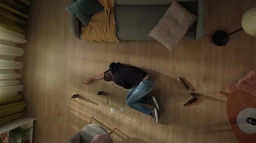 Top View of a Man Lying on the Living Room Floor Among Empty Bottles Pills Syringes The Man is