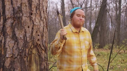 A Bearded Lumberjack Emerges From Behind a Tree with an Axe on His Shoulder