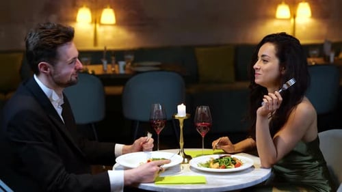 Happy Man and Woman Having Romantic Dinner in the Restaurant While Eating Salads and Toasting with