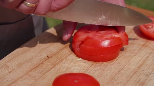Tomato being Sliced on a Wooden Cutting Board
