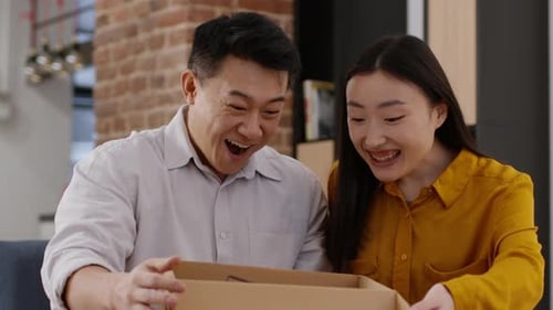 Couple Opening Package Together at Home with Delight