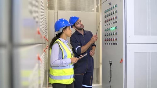 Two engineer or technician worker discuss about electrical panel in the construction site to check