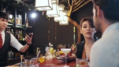 4K Caucasian woman using mobile phone making online payment scan QR code at restaurant bar.