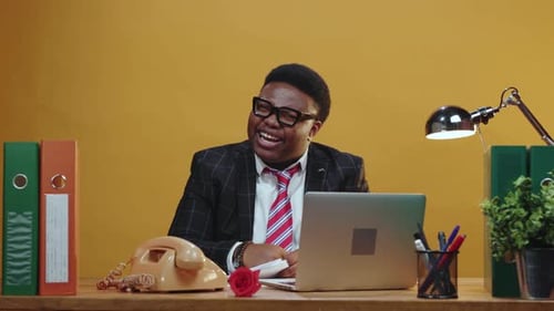 Man in suit at desk gestures excitedly