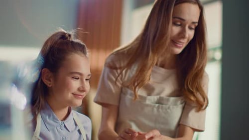 Cheerful Woman And Girl Cracking Eggs In Mixing Bowl On Domestic Kitchen In Slow Motion. Mother A...