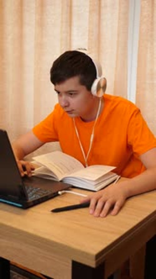 Teenager Studying with Laptop and Headphones at Desk