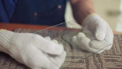 Hands Wearing Gloves Inspect Broken Piece of Glass