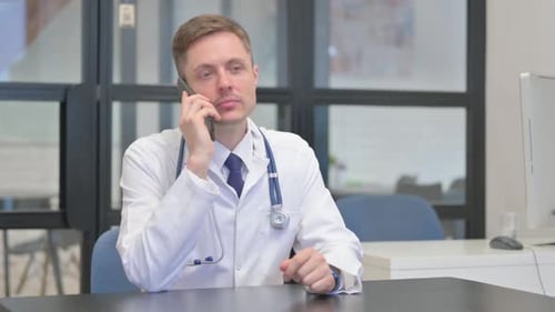 Doctor Talking on Phone at Desk in Office