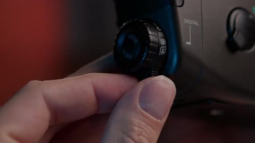Videographer Adjusting Digital Camera Focus Dial with Icons Selecting Modes and Settings for