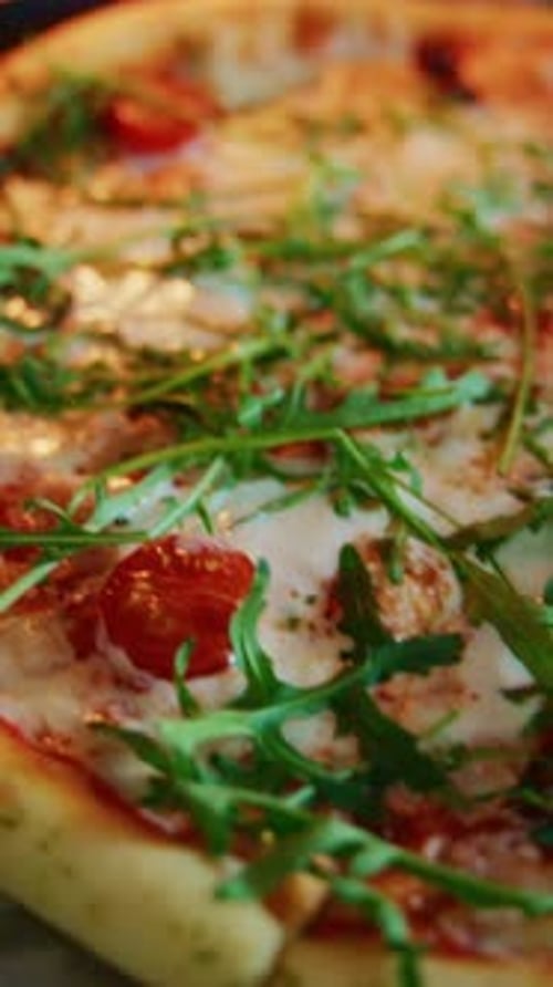 Delicious Pizza Topped with Fresh Arugula and Cherry Tomatoes in a Cozy Restaurant Setting