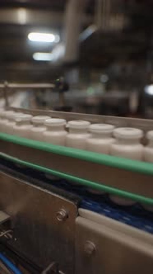 Plastic Jars with White Caps Moving on Industrial Conveyor