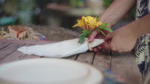 Person Decorates Table with Flower and Napkin