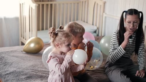 Children Blowing up Balloons for a Birthday Party