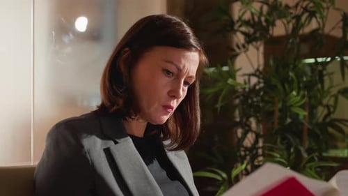 Businesswoman Reading Documents with Serious Expression Indoors