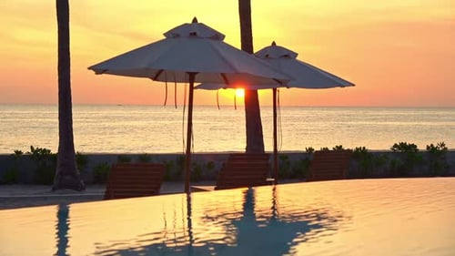 Amazing shot of sea view resort with infinity pool and sun umbrellas at sunset