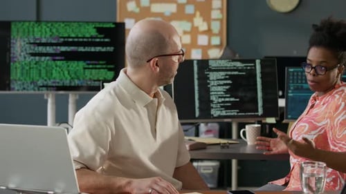 Multiethnic IT Specialists Discussing Program Development in Open Space Office