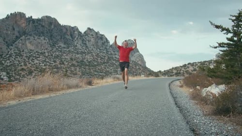Man Runs on Road Near Rocky Mountains