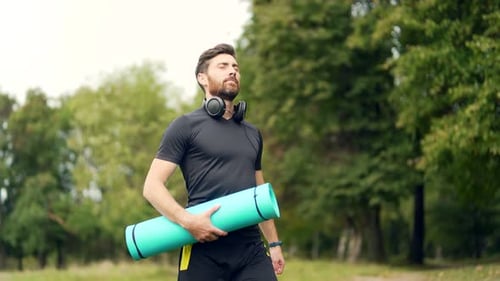 Aktiver gutaussehender männlicher Yogi geht vor oder nach dem Training in einem Park spazieren und durch den Wald. Jung bärtig