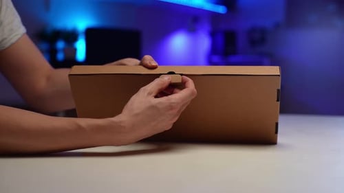 Closeup Unrecognizable Male Hands Unboxing Cardboard Box with New PC Hardware Sitting at Desk in