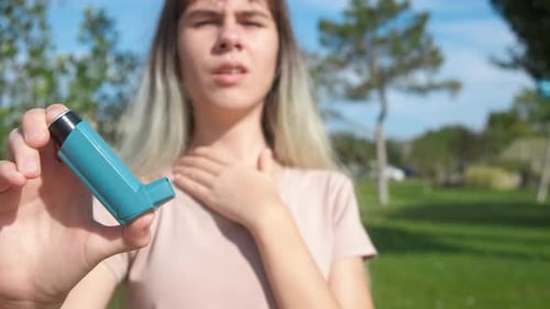 Young Adult Holding Asthma Inhaler Outdoors