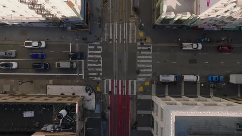Birds Eye Shot of Cross Shape Road Intersection Surrounded By Town Development Vehicles Driving in