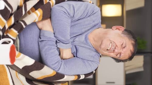 Man Wrapped in Blanket Coughing Indoors