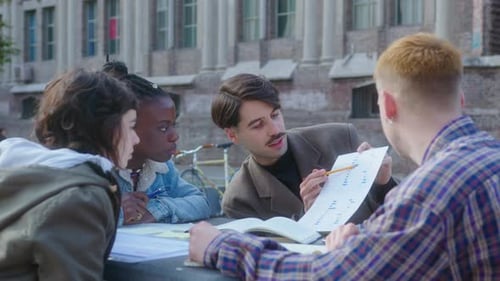 College Students Discussing Graph on Paper Outdoors on Campus