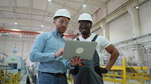 Two Diverse Workers in Production Plant As Team Discussing Industrial Scene in Background