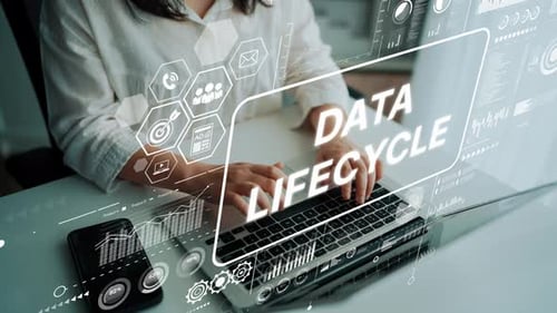 Professional Woman Typing on Laptop with Data Lifecycle Graphics Overlaying Modern Office Environmen