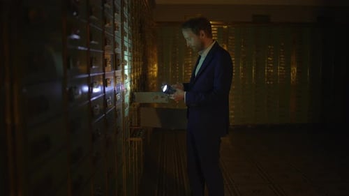 Man Opens Safety Deposit Box with Flashlight at Night