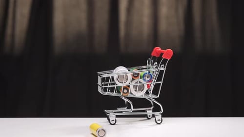 Hand Placing Batteries Into Miniature Shopping Cart