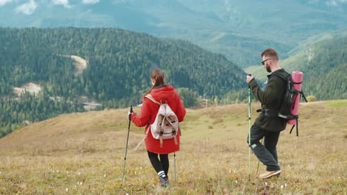Couple Hiking Scenic Mountain with Trekking Poles