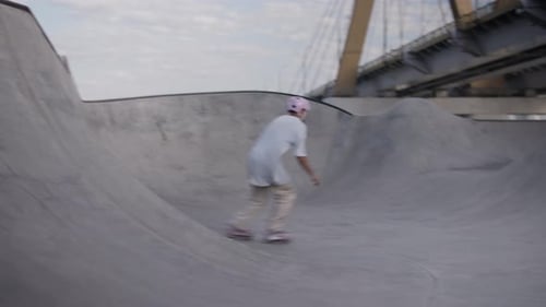 Un patineur en ligne agressif parcourt rapidement une rampe dans un skatepark près d'un pont