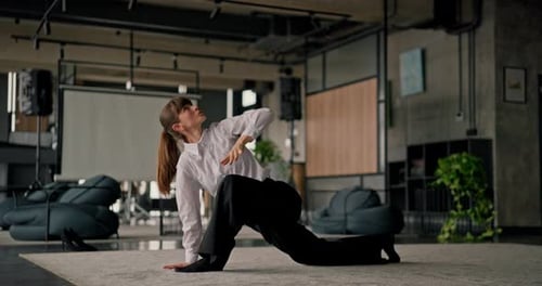An Office Worker Girl Stretches Her Legs and Back During a Yoga Session on a Mat in the Office