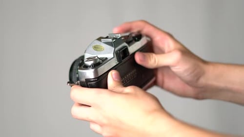 Hands advance film lever and take photo with vintage camera, close-up